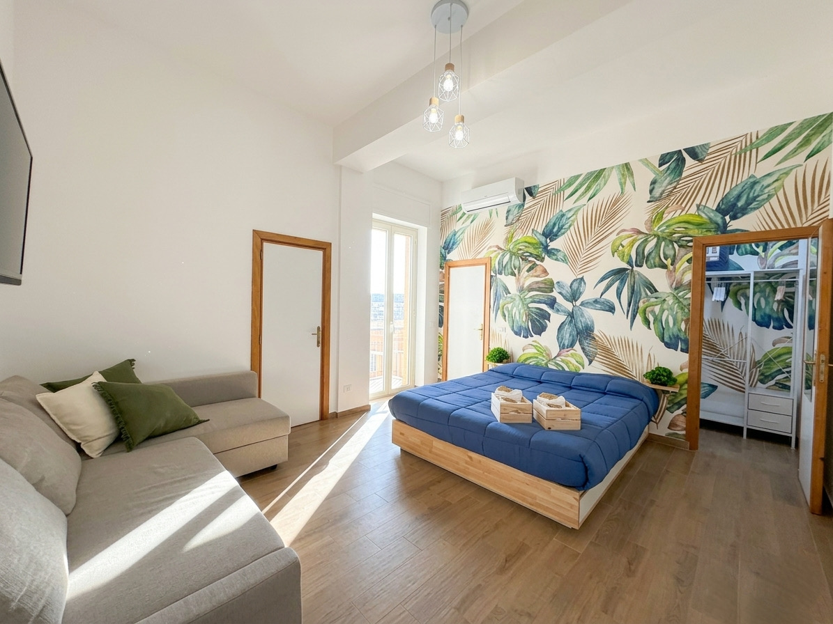 Soggiorno con letto matrimoniale e carta da parati tropicale